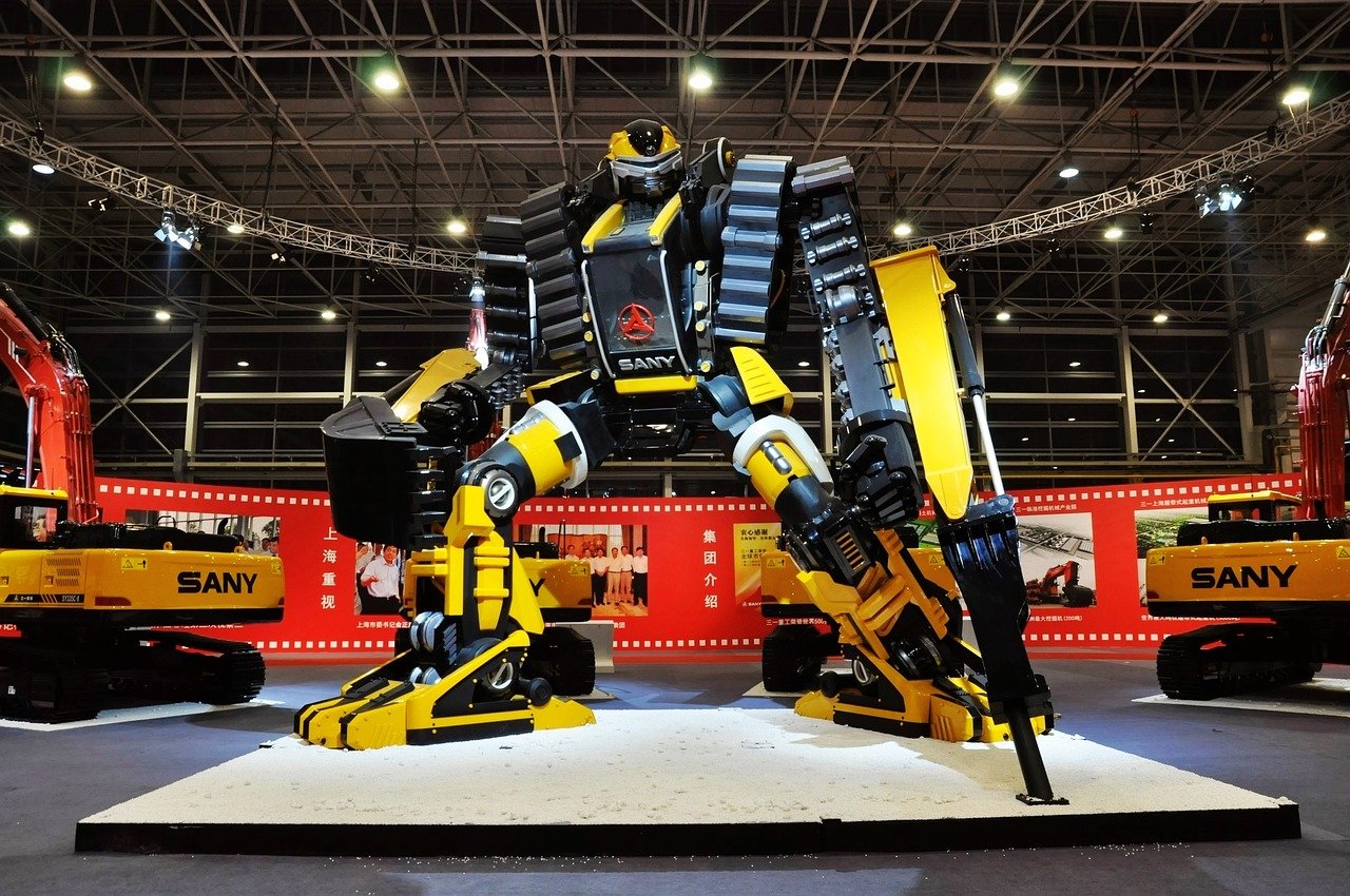 Large yellow and black humanoid robot with jointed arms and legs on display at an exhibition