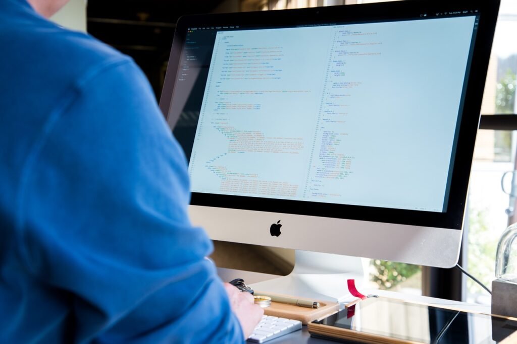 A person working at a desktop computer with code on the screen