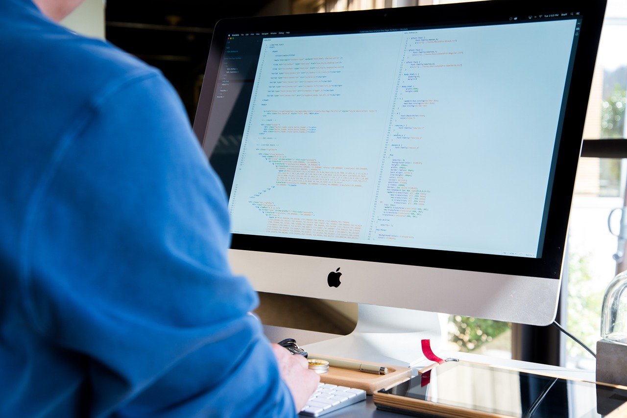 A person working at a desktop computer with code on the screen