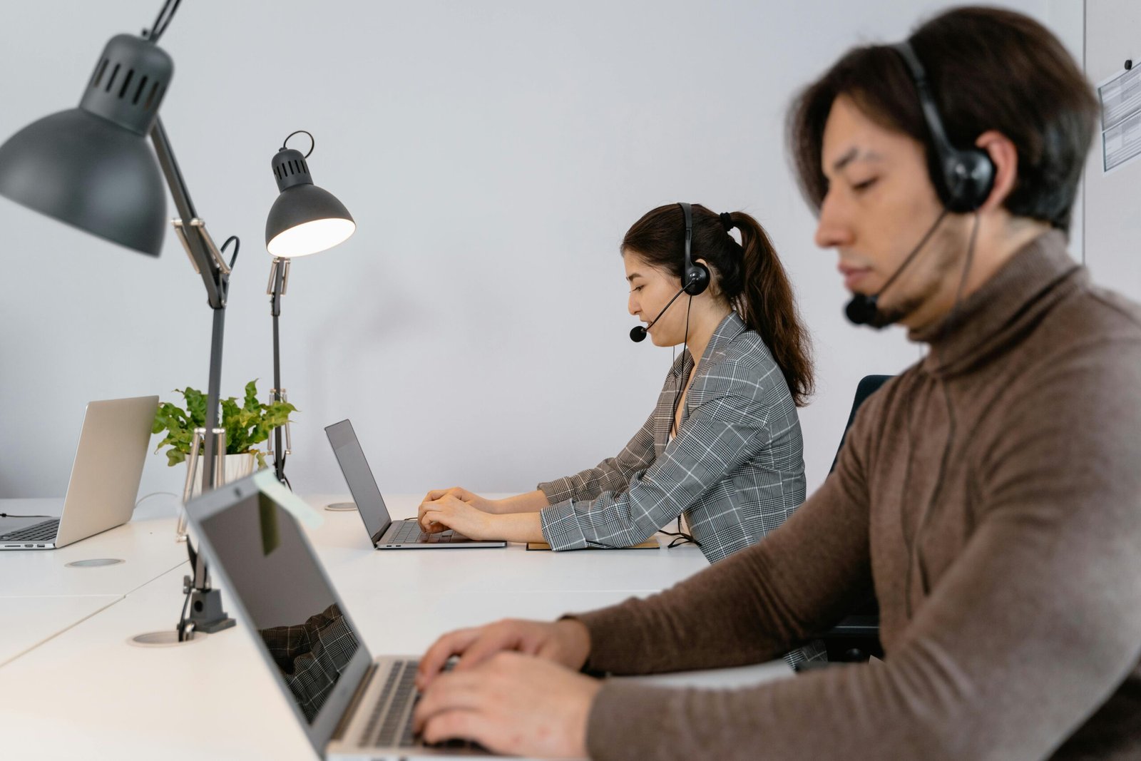 Two people working at laptops with headsets, reviewing examples for fine-tuning an AI model