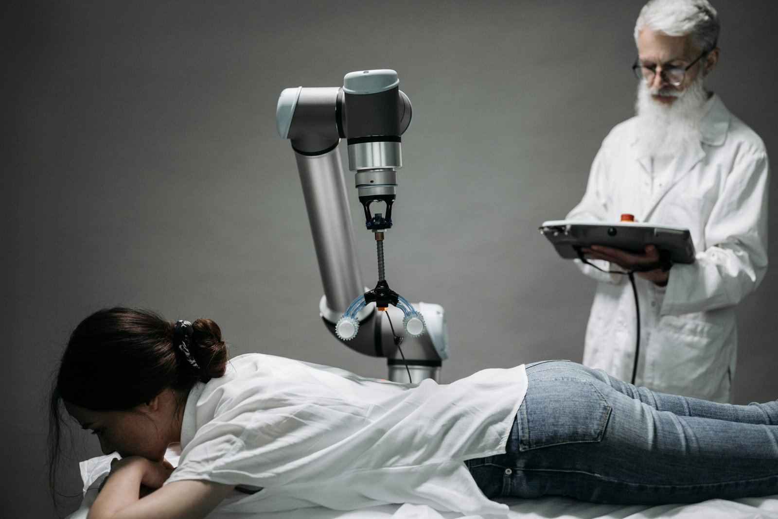 A person using a tablet beside a robotic arm in a workshop