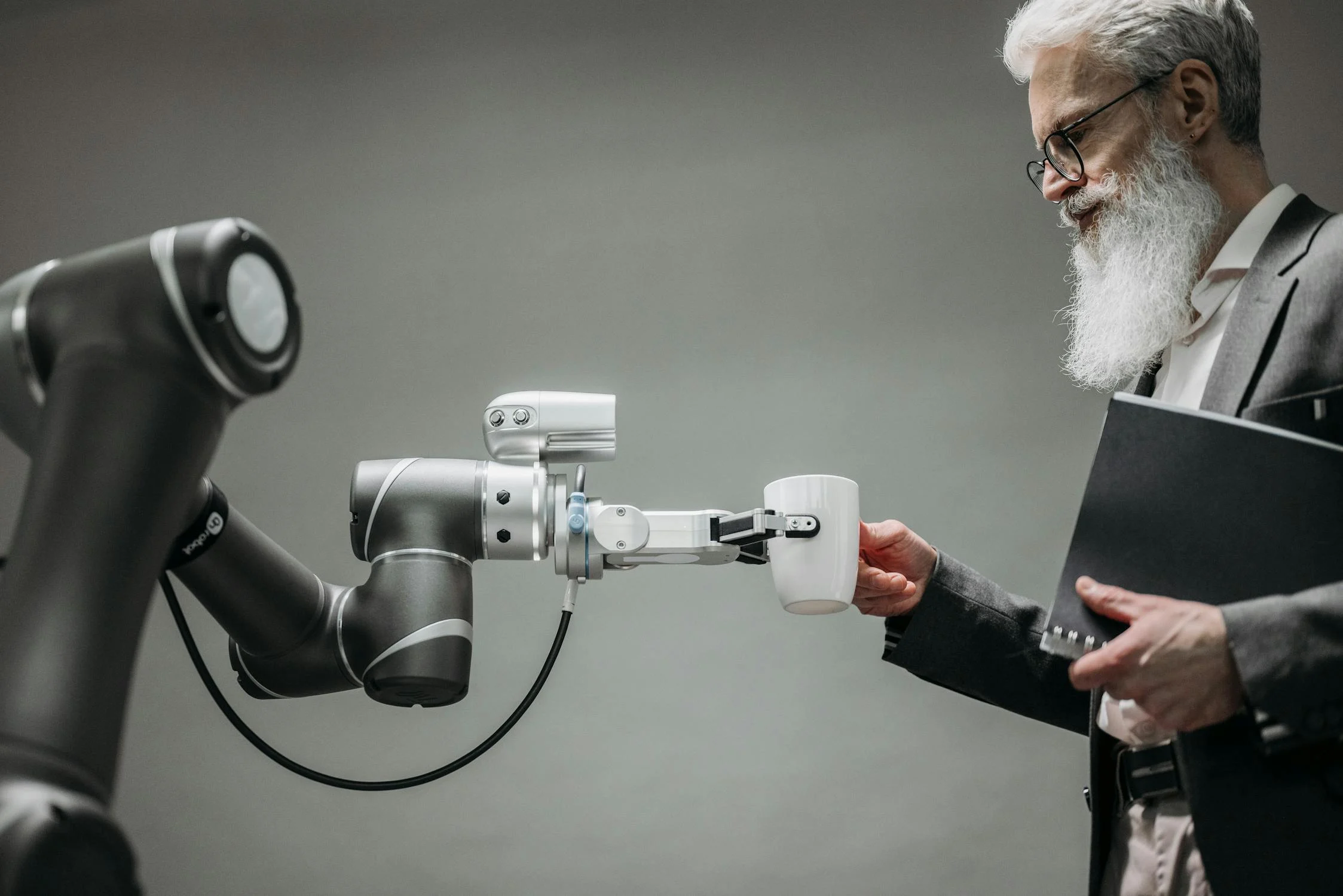 A robotic arm handing a white cup to a person